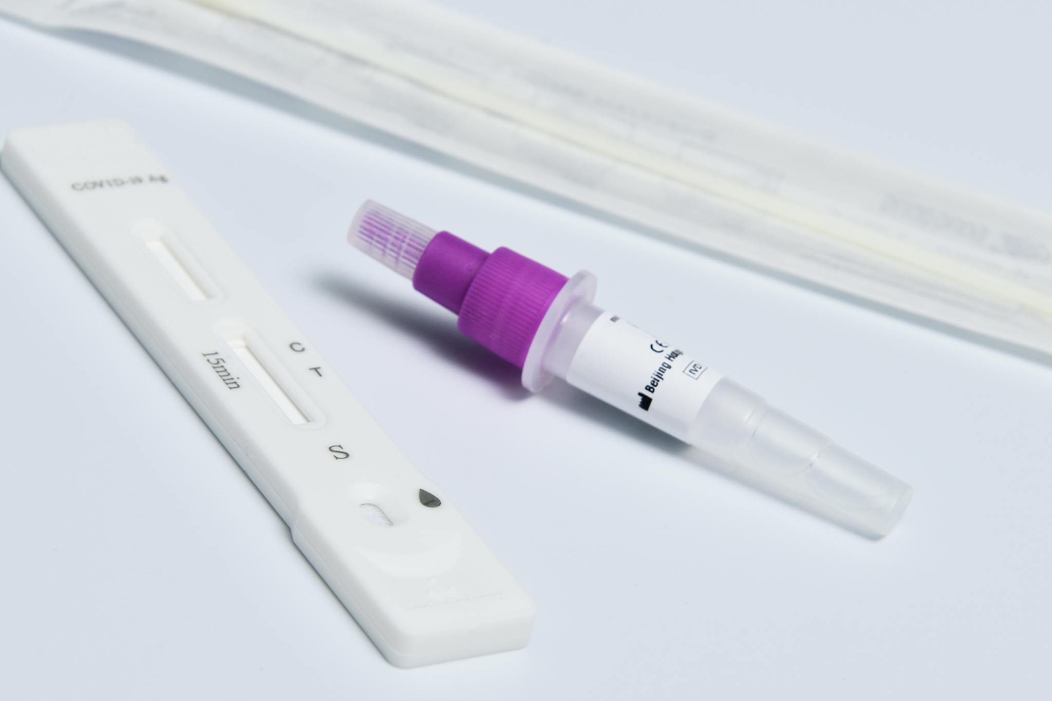 Close-up of a COVID-19 rapid antigen test kit with a dropper and swab on a white surface.