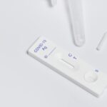 Close-up of a COVID-19 rapid antigen test kit with swab on a white surface.