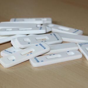 Close-up of several Covid-19 rapid test kits scattered on a wooden table.
