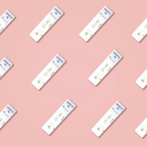 Multiple Covid-19 antigen test kits arranged on a pink surface, ideal for health-related content.